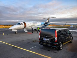 Two men walking from a luxury car to a private jet wth red carpet at Access Oslo FBO