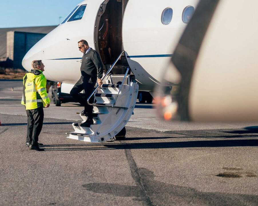 Two men by the stairs of a small aircraft for VIP handling at Bergen FBO ENBR