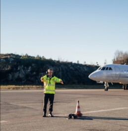 Man in yellow jacket marshalling small jets at the terminal in Bergen